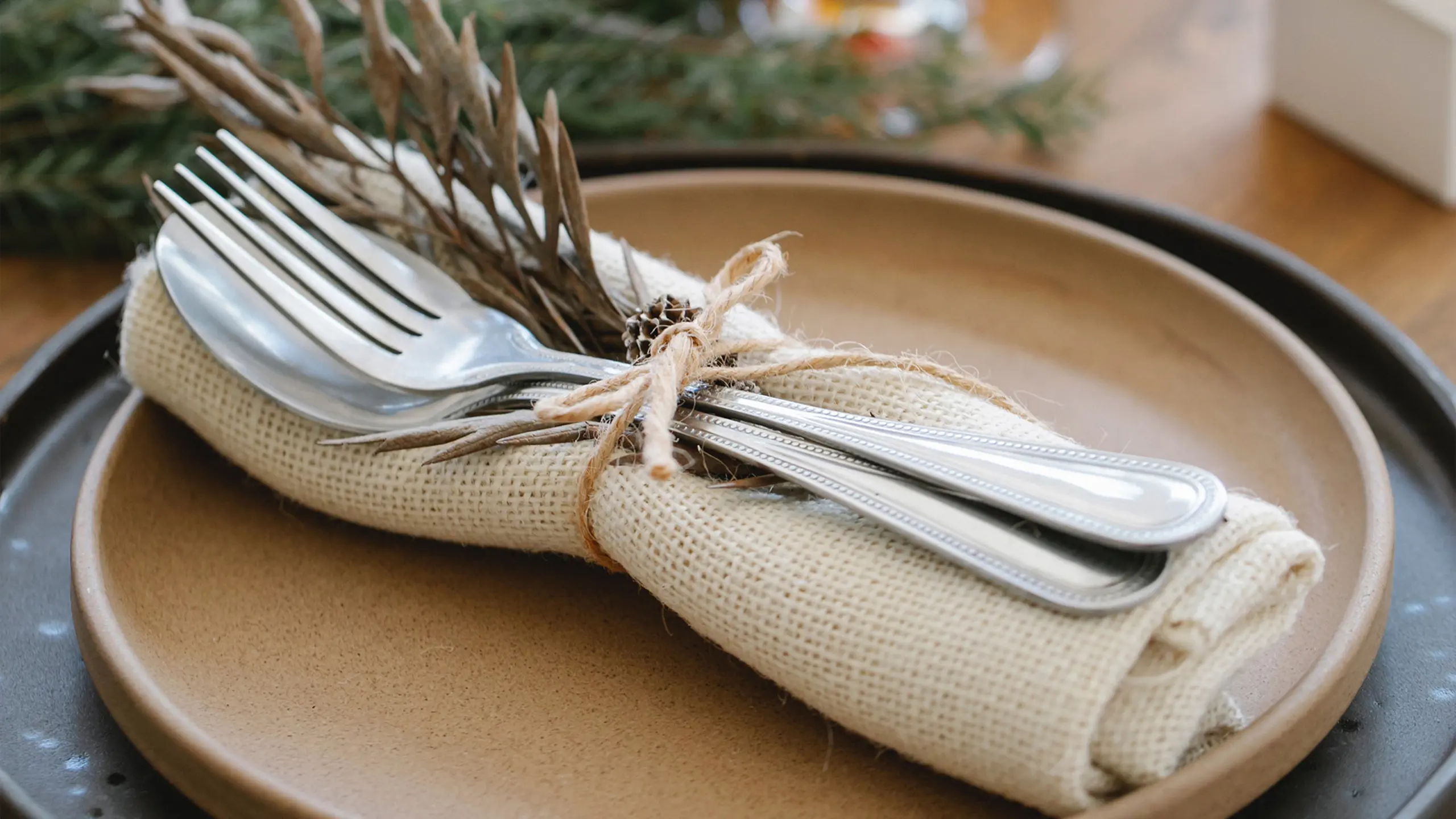  Borddækning Med To Tallerkner Med Stofserviet Og Bestik Og Gran Bundet Med Sejlgarn